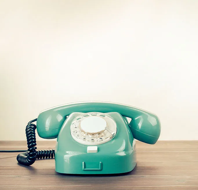 Vintage green rotary dial telephone on wooden desk. Jetsetters – luxury travel advisor Oslo.
