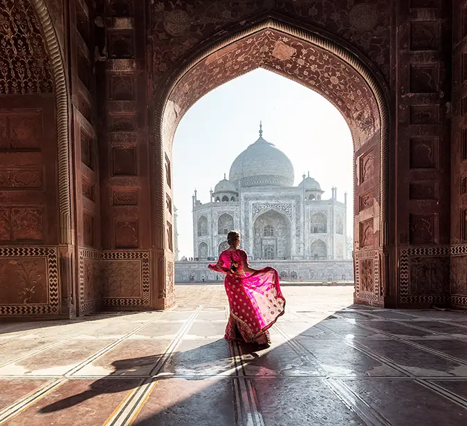 A woman wearing a saree standing in front of Taj Mahal in Agra, India