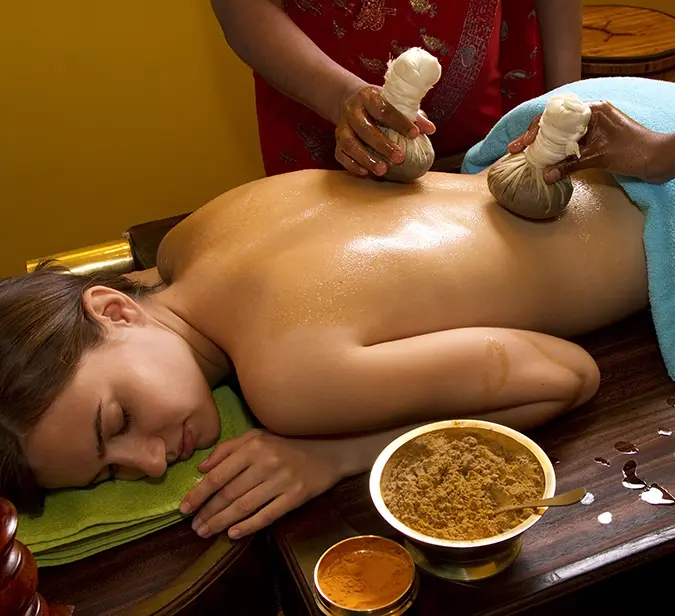 Traditional Ayurveda spa treatment with herbal poultices at a luxury wellness retreat in India.