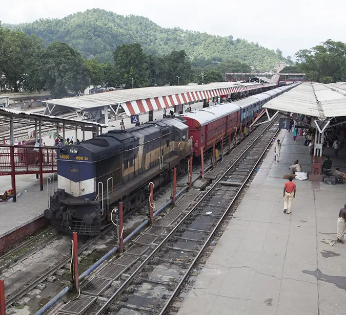 Train ready for departure at Haridwar railway station surrounded by scenic hills and greenery.
