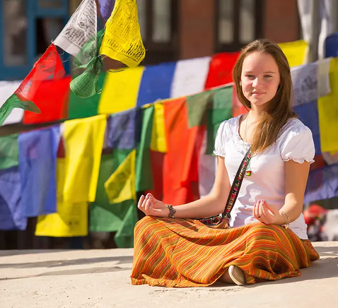 Woman meditating in front of colourful prayer flags in Kathmandu, Nepal.