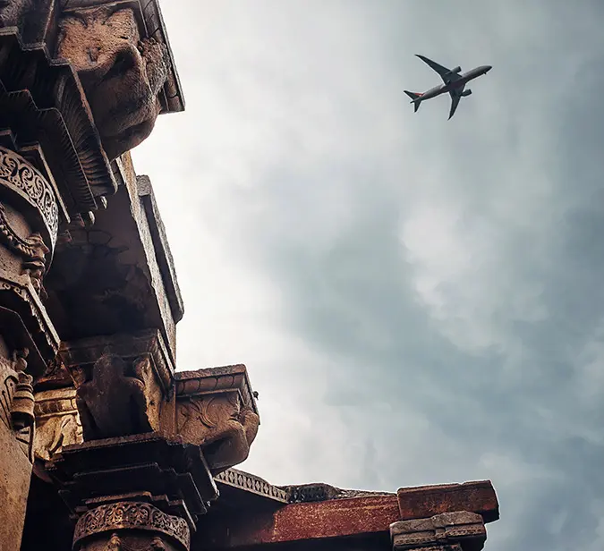 Airplane flying over Qutub Minar, historic UNESCO World Heritage Site in Delhi, India.