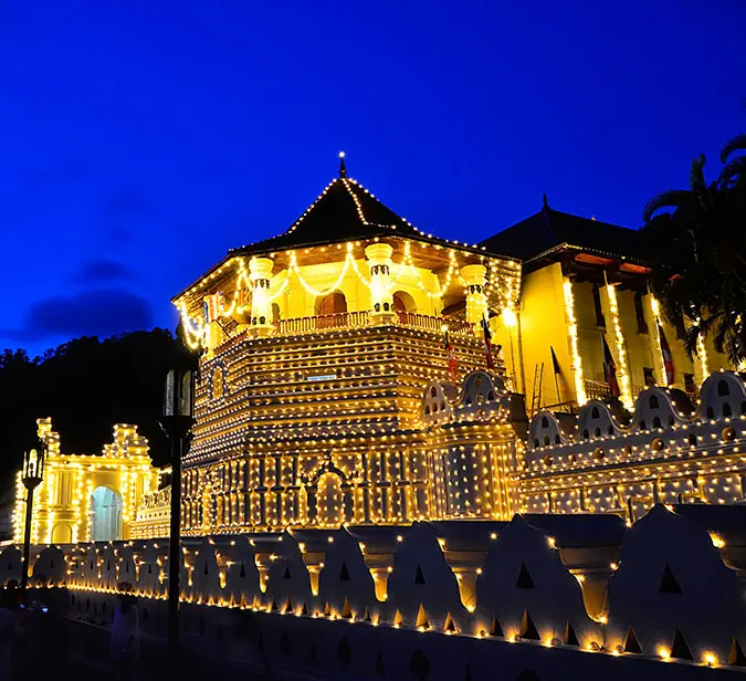 Temple of the Tooth adorned with golden lights, reflecting Kandy’s spiritual grandeur.