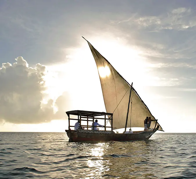 Traditional dhow sailing at sunset near Mnemba Island.