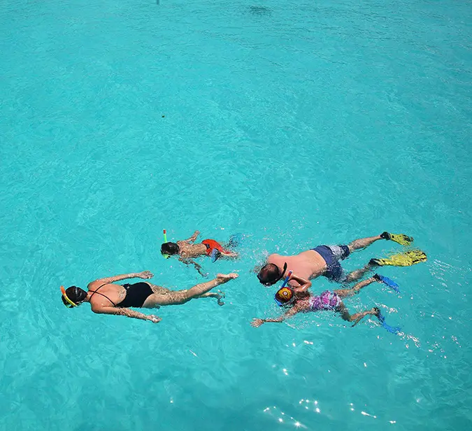 Family explores vibrant marine life while snorkeling around Mnemba Island near Zanzibar.