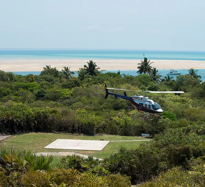 Helicopter departing Benguerra Island with turquoise ocean views in the background.