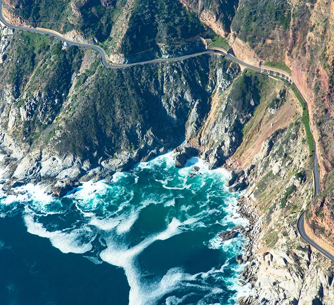 Aerial view of coastal cliffs and winding road near Cape Town’s dramatic shoreline.