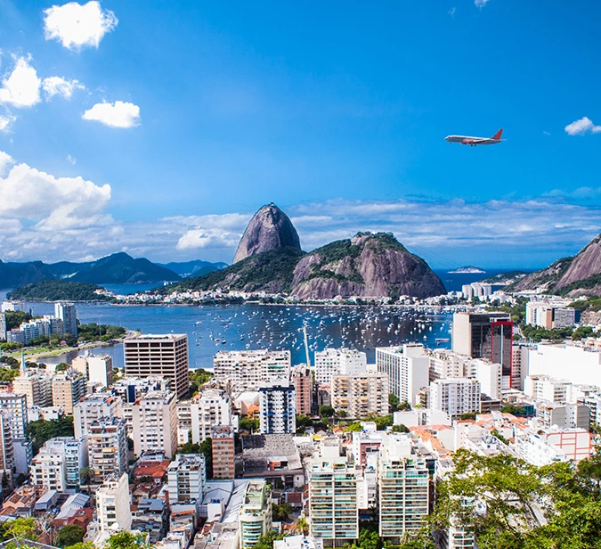 Airplane departing over Rio de Janeiro with Sugarloaf Mountain and skyline below.