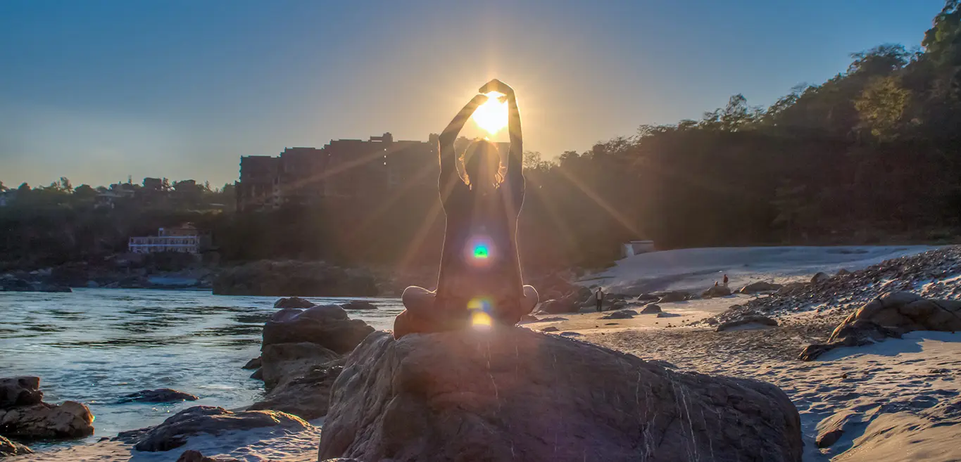 Woman practicing yoga at sunrise on riverbank near Himalayas, embracing peace and nature’s energy.
