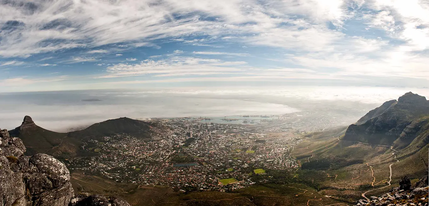 Panoramic view of Cape Town from Table Mountain under a dramatic sky.